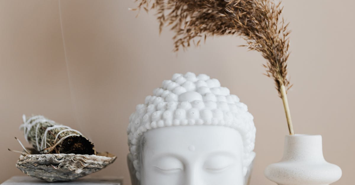 Vase with dried herb arranged with Buddha bust and sage smudge stick in bowl