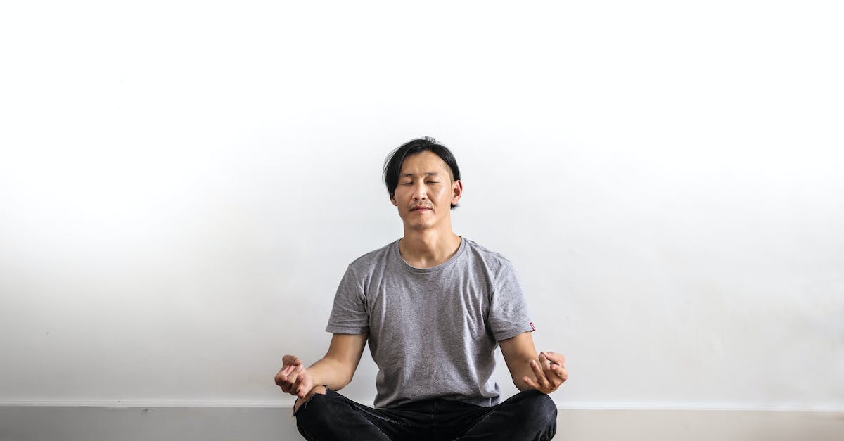 Photo of Man in Gray T shirt and Black Jeans on Sitting on Wooden Floor Meditating 6